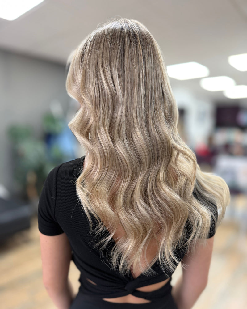 Person with long, wavy blonde hair in a salon setting